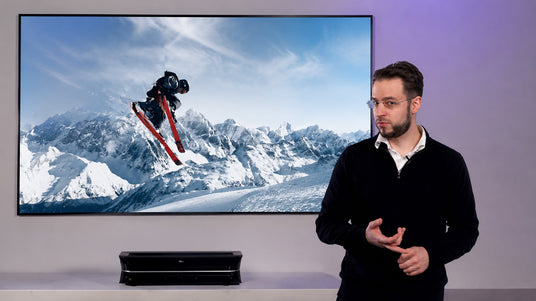 Mann stellt AWOL Vision LTV3000 Pro Laser TV vor Skisprung-Bild