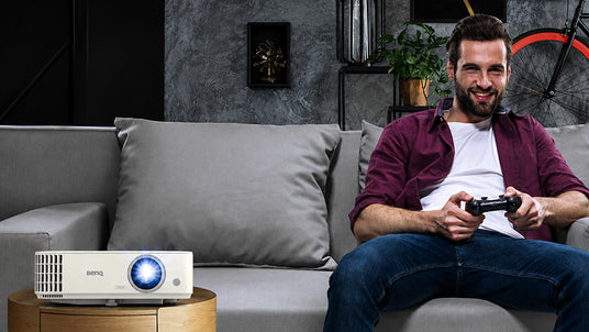 BenQ TH685i Beamer für Gaming und Streaming neben Mann mit Gamepad